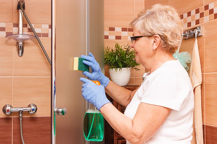 Older woman cleaning bathroom shower