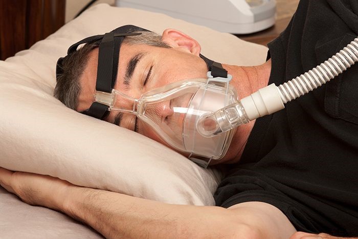 Photo of man with sleep apnea wearing cpap machine.