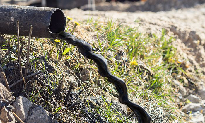 Image: Oil draining from a pipe directly onto soil.