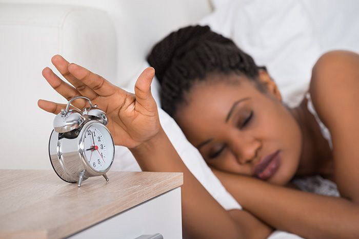 Image of woman reaching for alarm clock