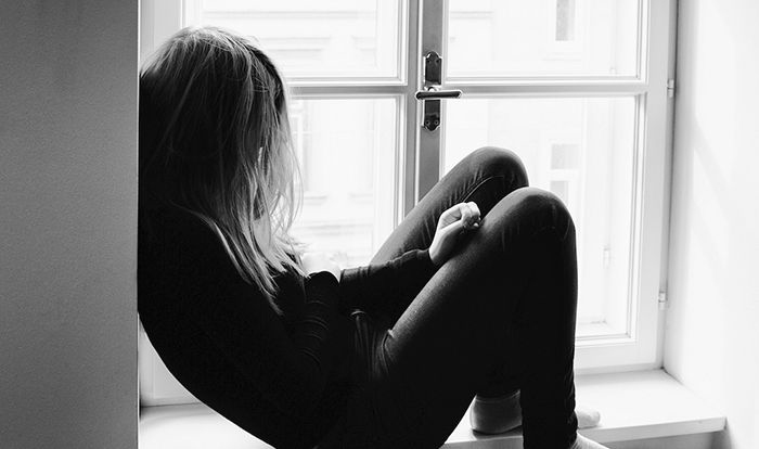 Image of teenager sitting on windowsill.