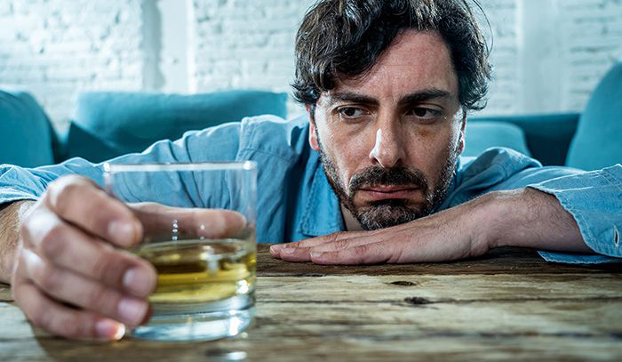 Image of man staring at a glass of alcohol