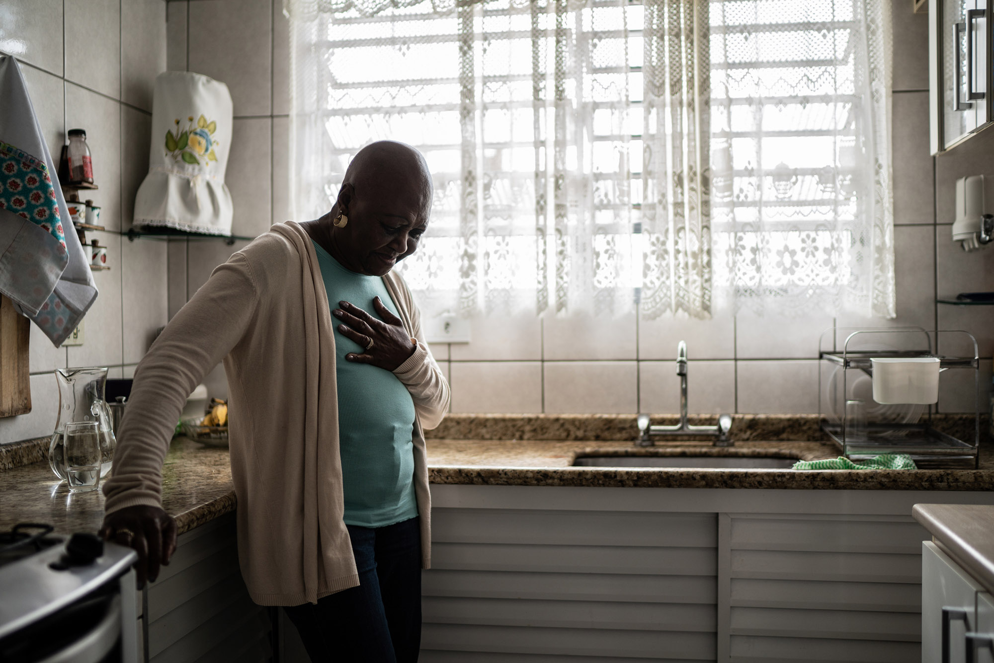 "Experiencing Racism Increases Black Women’s Heart Disease Risk, BU Research Finds; Stock photo of older woman inkitchen with hand over chest"
