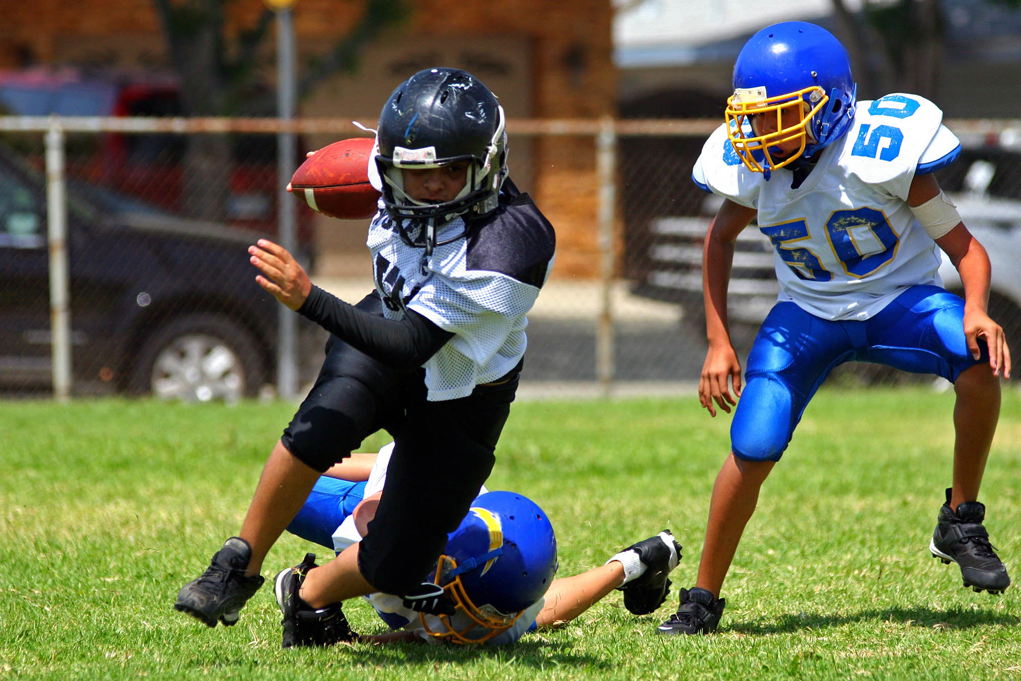 New BU Study Finds Tackle Football at Young Age Raises Risk for Brain Decline Later; Stock image of kids playing football