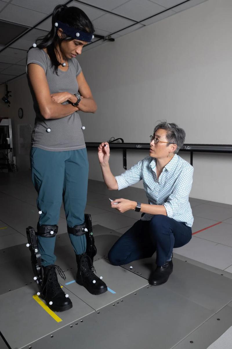 To Help Recover Balance, Robotic Exoskeletons Have to be Faster Than Human Reflexes; "Lena Ting, right, applies motion capture sensors to Surabhi Simha for a standing balance test with robotic ankle exoskeleton boots."