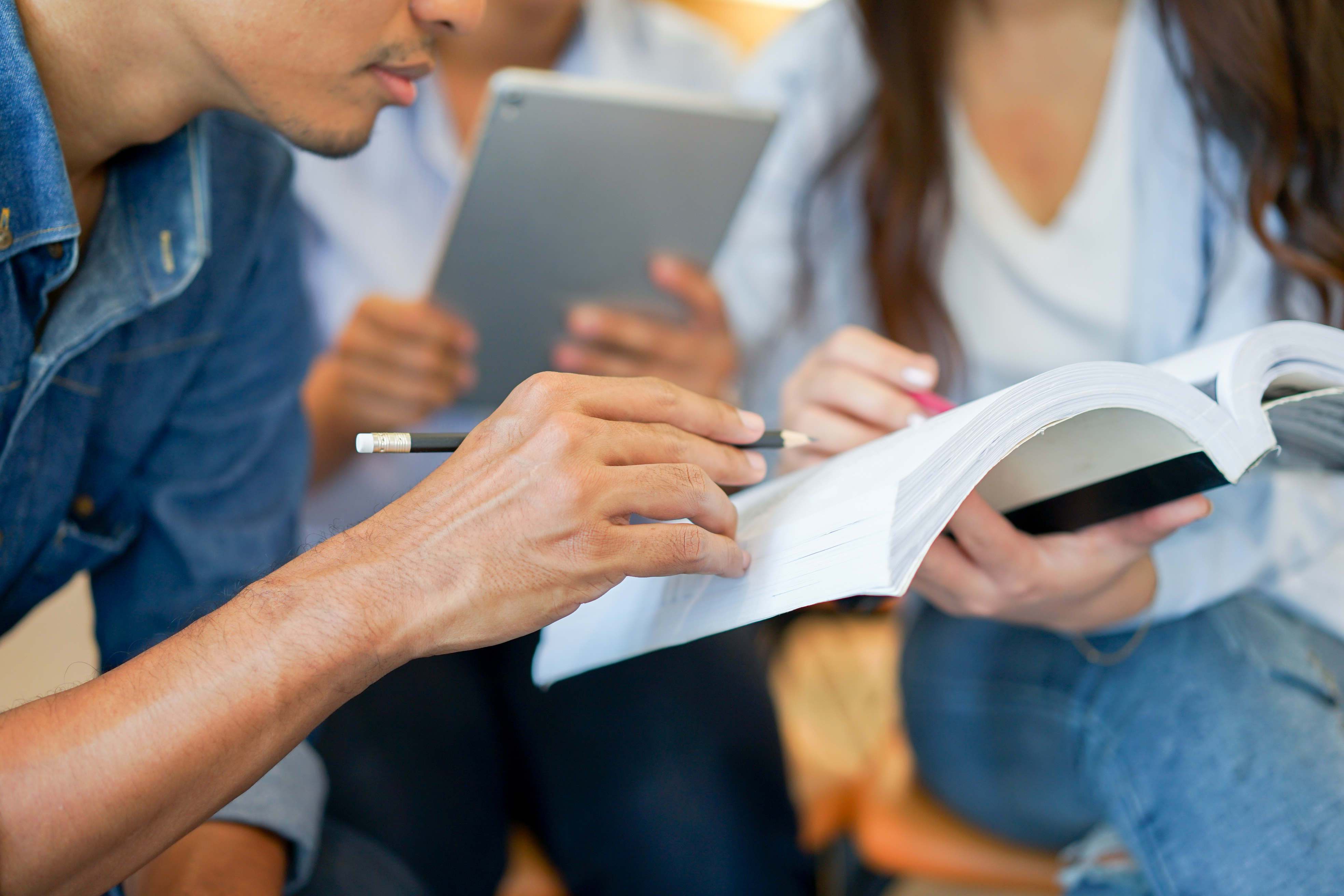Close up of a student explaining something with a book in his hand