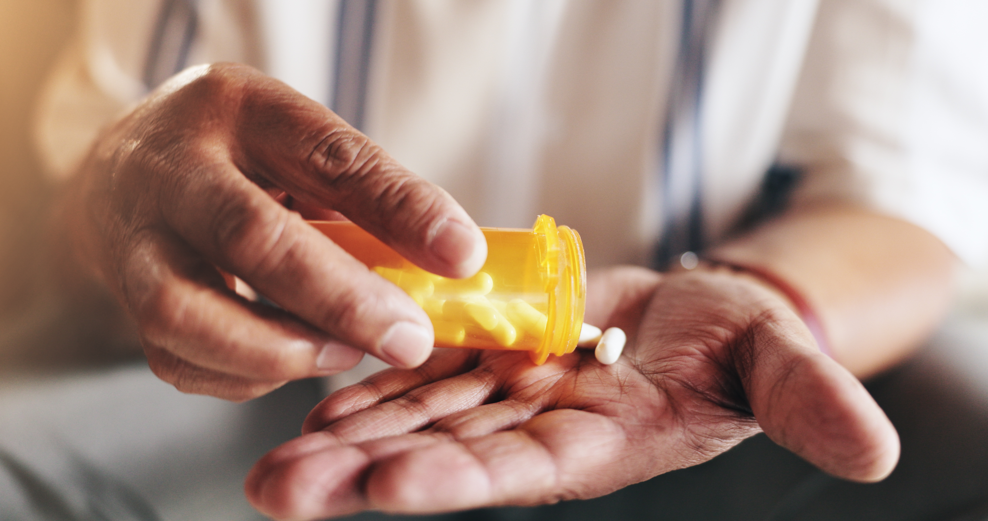 A patient pouring pills out of a prescription medication bottle.