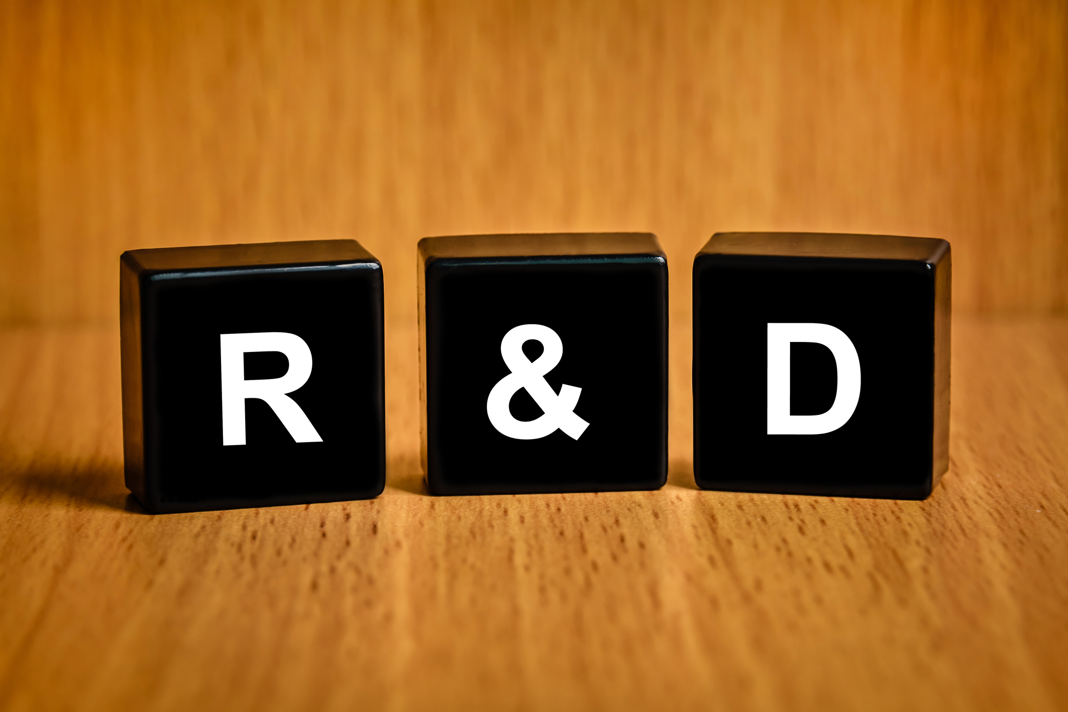 Black wooden blocks spell out R&D in white lettering.