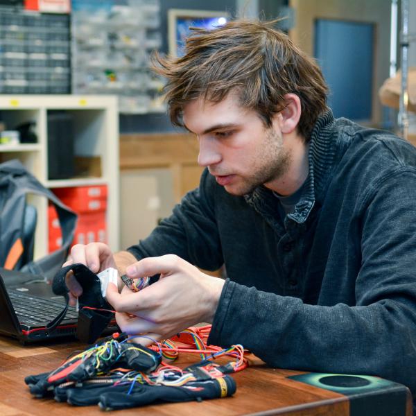Technology, Arts and Media student Kristof Klipfel works at a computer with his "piano gloves"