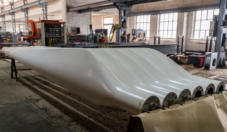 Two sets of new blades for wind turbines in a factory floor. Photo licensed from Adobe Stock.