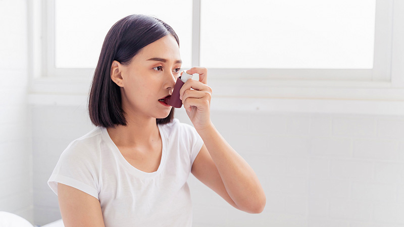 woman using inhaler to prevent an asthma attack