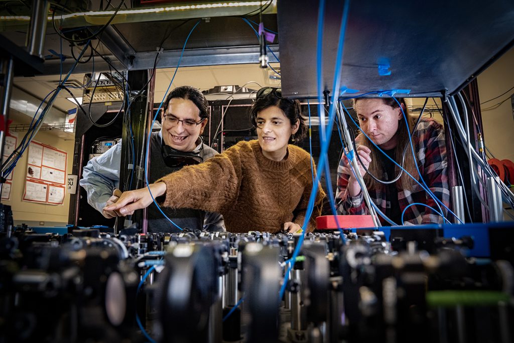 In his Stony Brook Quantum Information Laboratory, lead researcher Eden Figueroa, left, with his collaborators in research investigating quantum internet capacities, Sonali Gera, and Chase Wallace