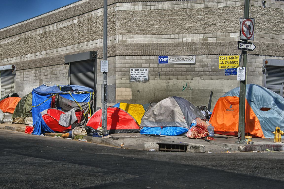 group of tents belonging to people experiencing homelessness on a street corner