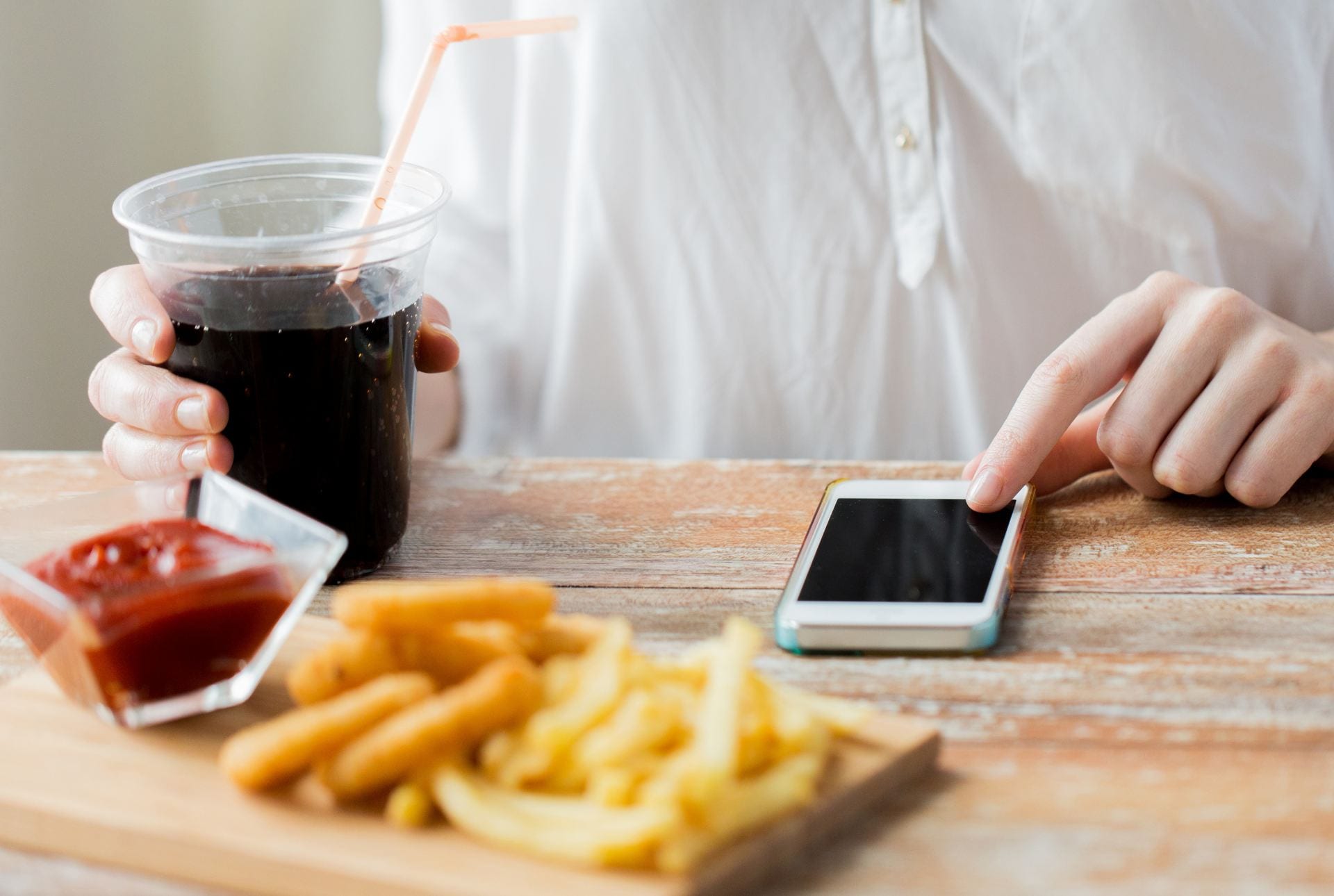 A person multitasks while eating fast food.