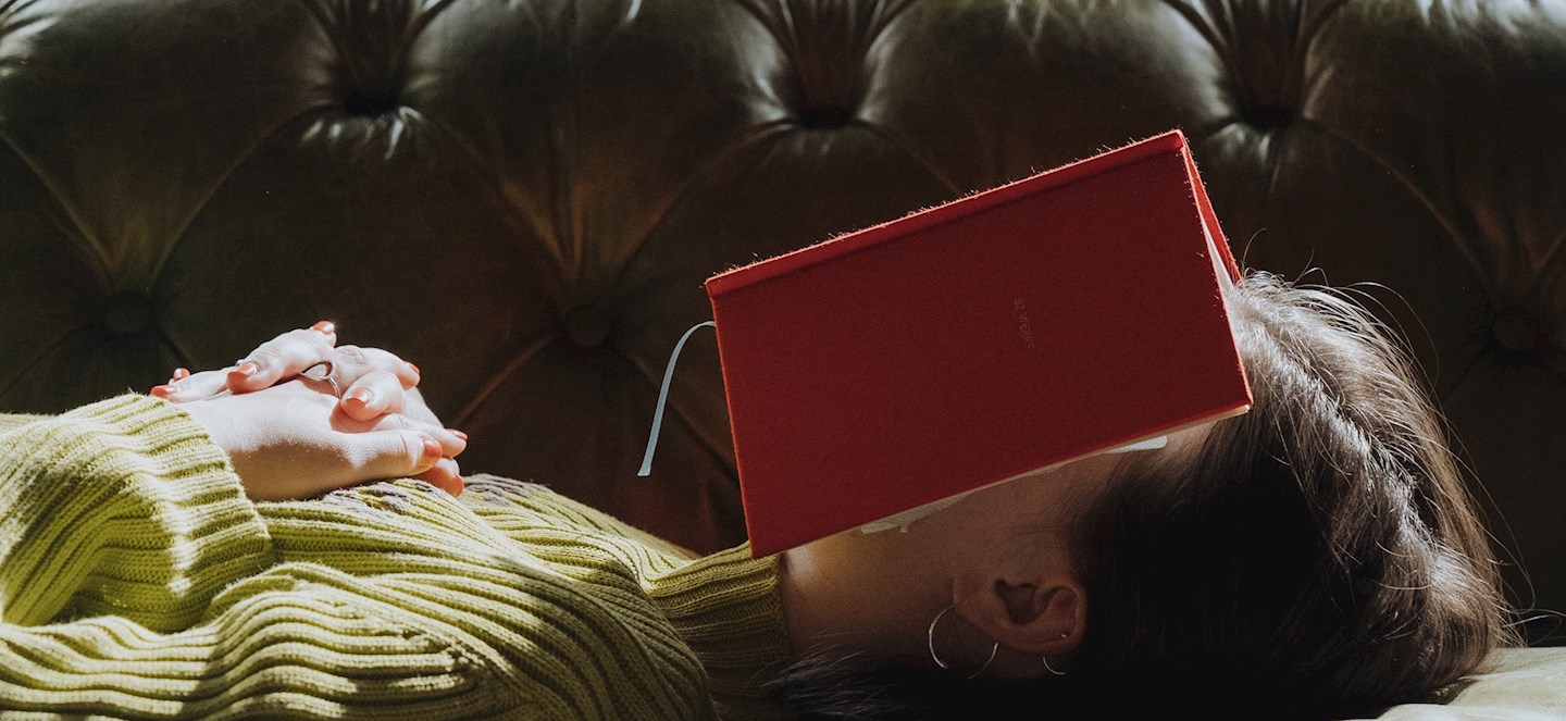 A person sleeping with a book on their face.