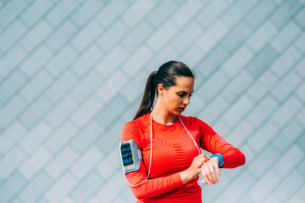A woman wearing athletic gear checks her smartwatch.