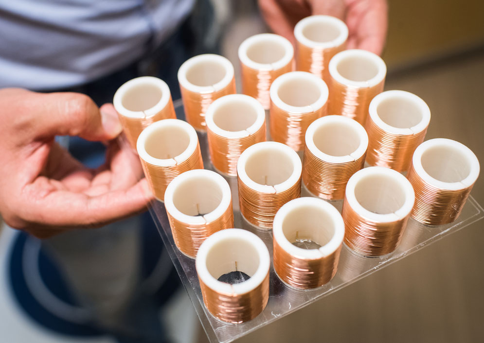 An array of helical resonators, which look like copper wire wrapped around a spool.