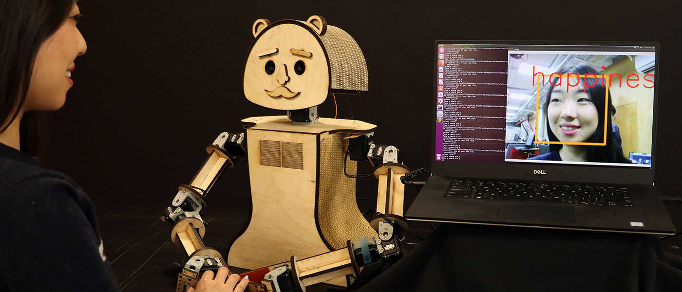 A woman and a small robot, which is learning to read her emotions