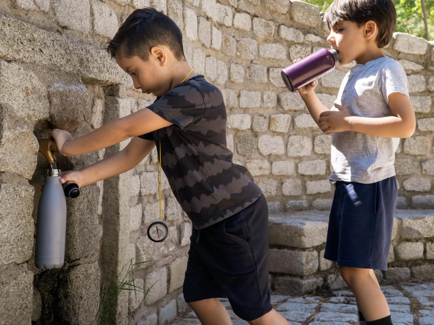 two children filling water bottles