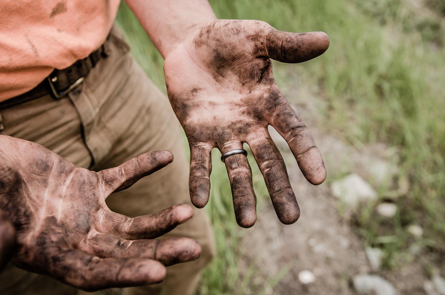 A man shows off his dirty hands.