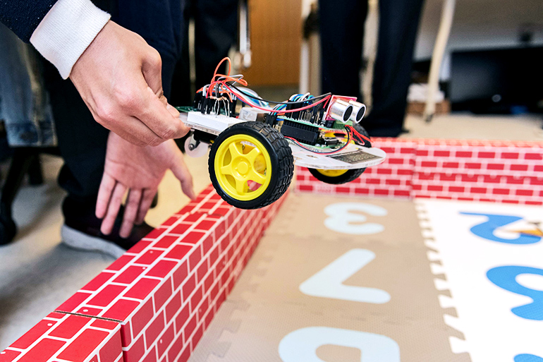 Hand sets down a small robot.