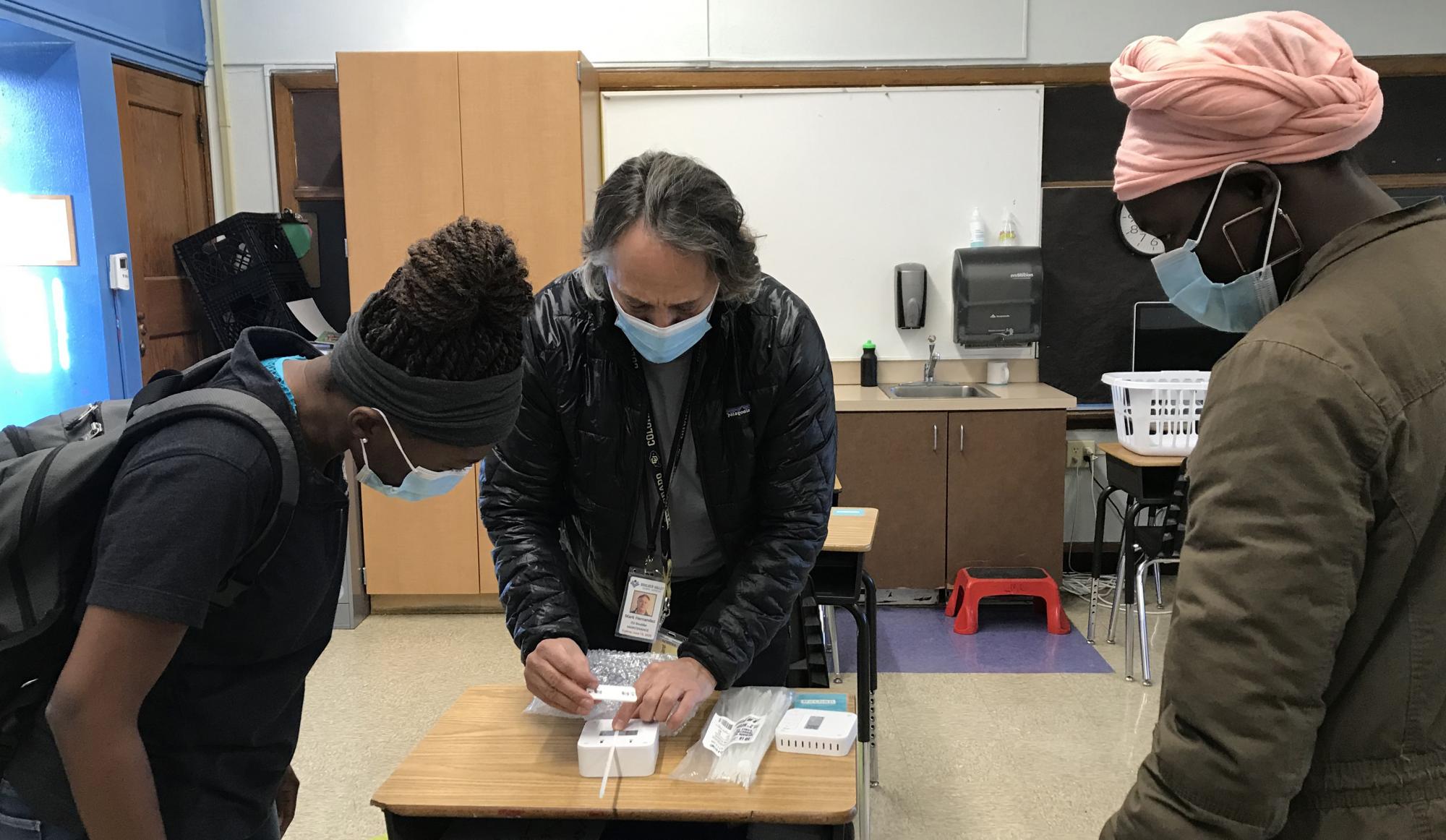 Professor Mark Hernandez demonstrates the installation process for the classroom air quality remote sensors