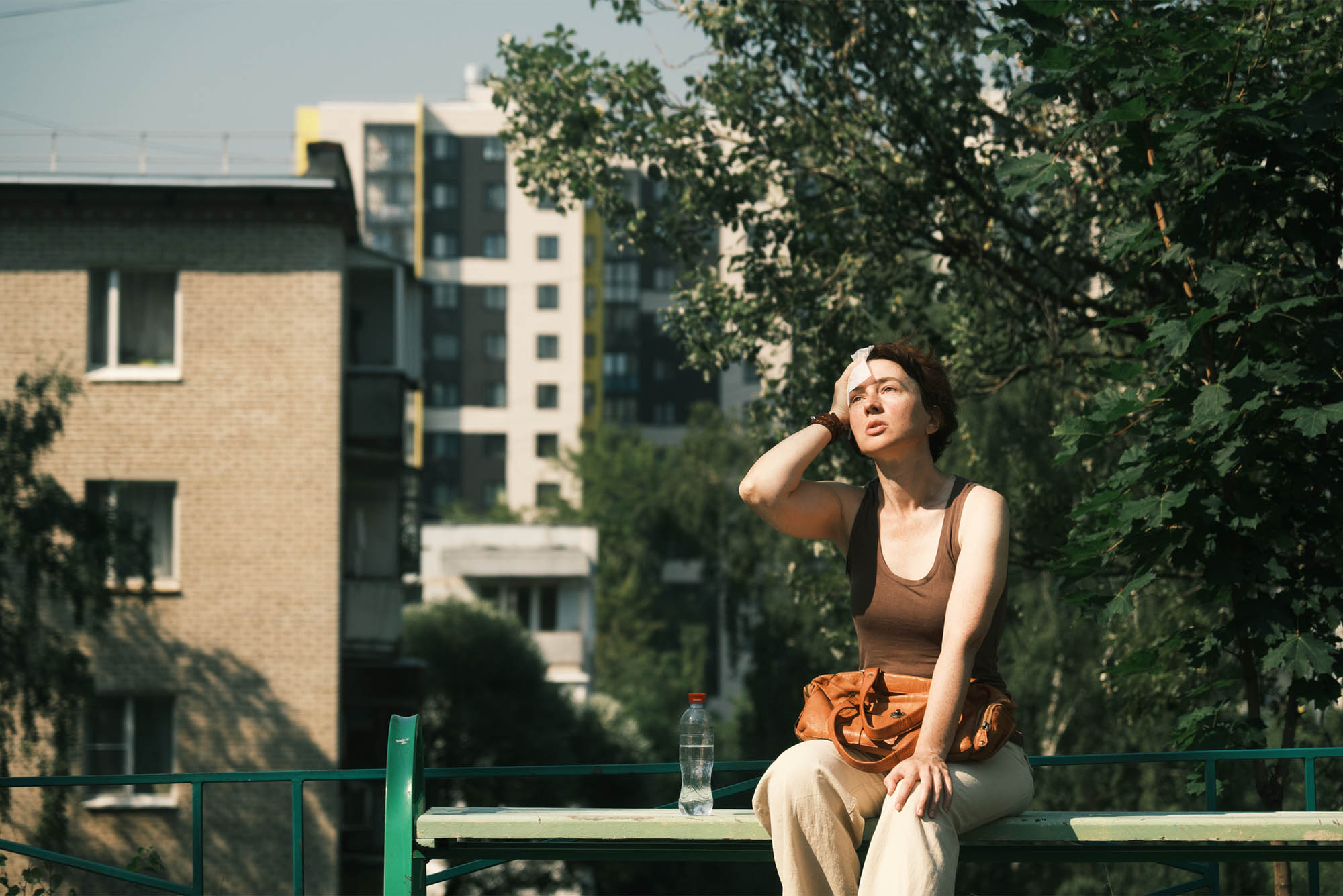 Woman sitting on a bench wiping forehead