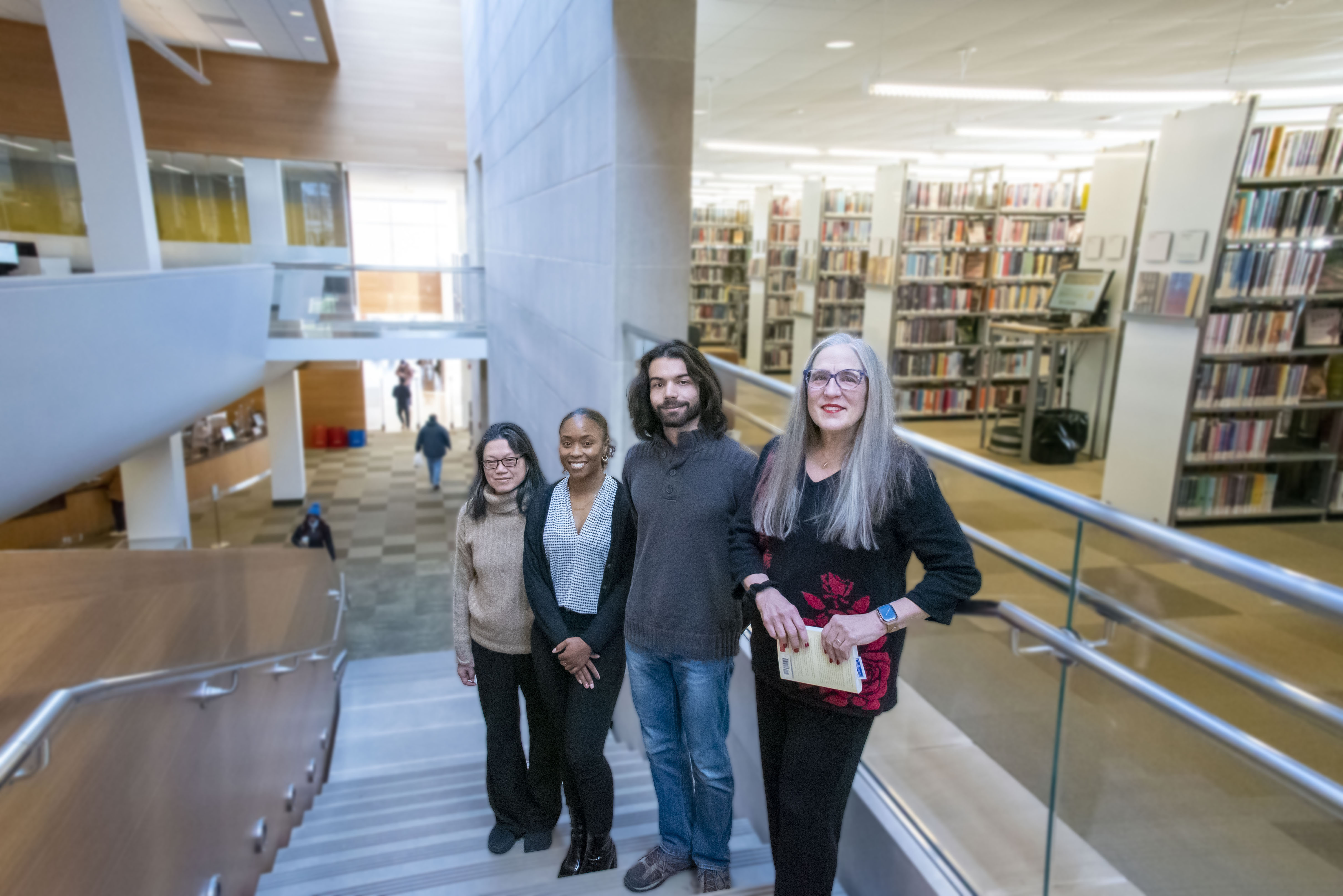 Four researchers posing for a picture on a staircase in a library