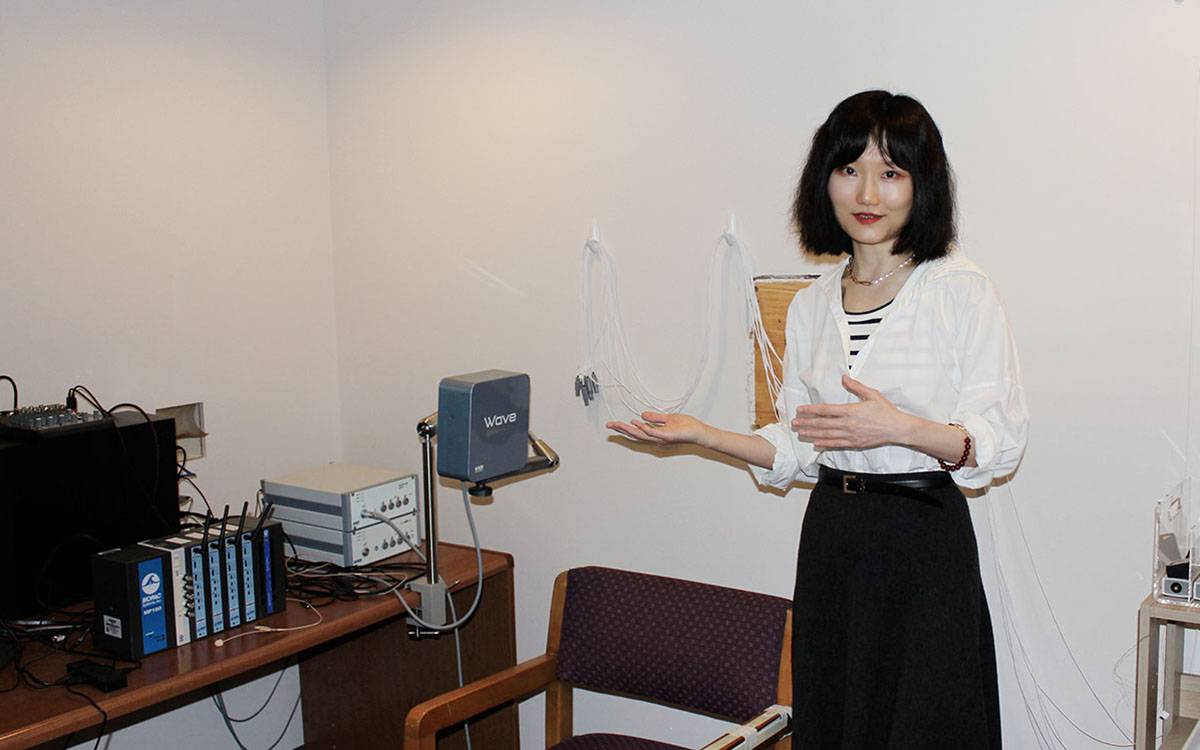 Researcher shows equipment in a lab that measures speech organs.