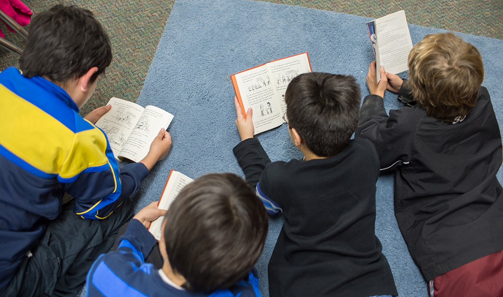 Children read books on the ground.