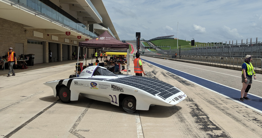 A solar-powered race car parked on the tarmac.