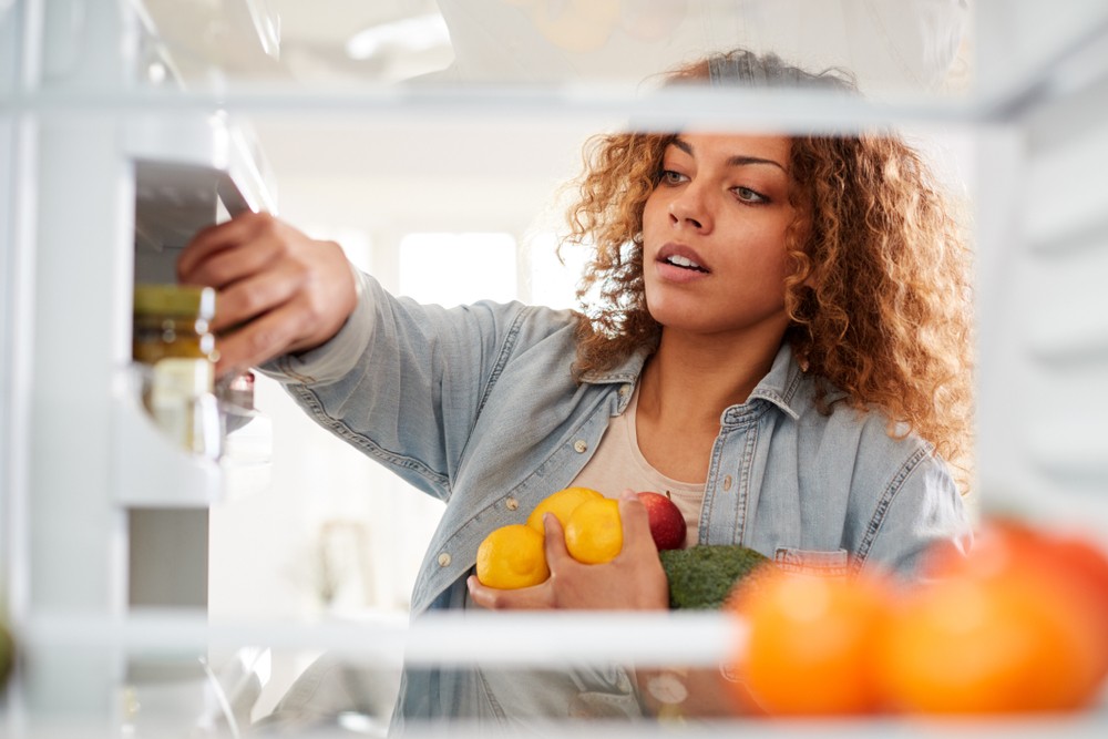 A woman reaches into a fridge.