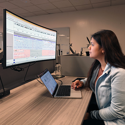 Researcher at a desk viewing genetic sequences on a computer screen
