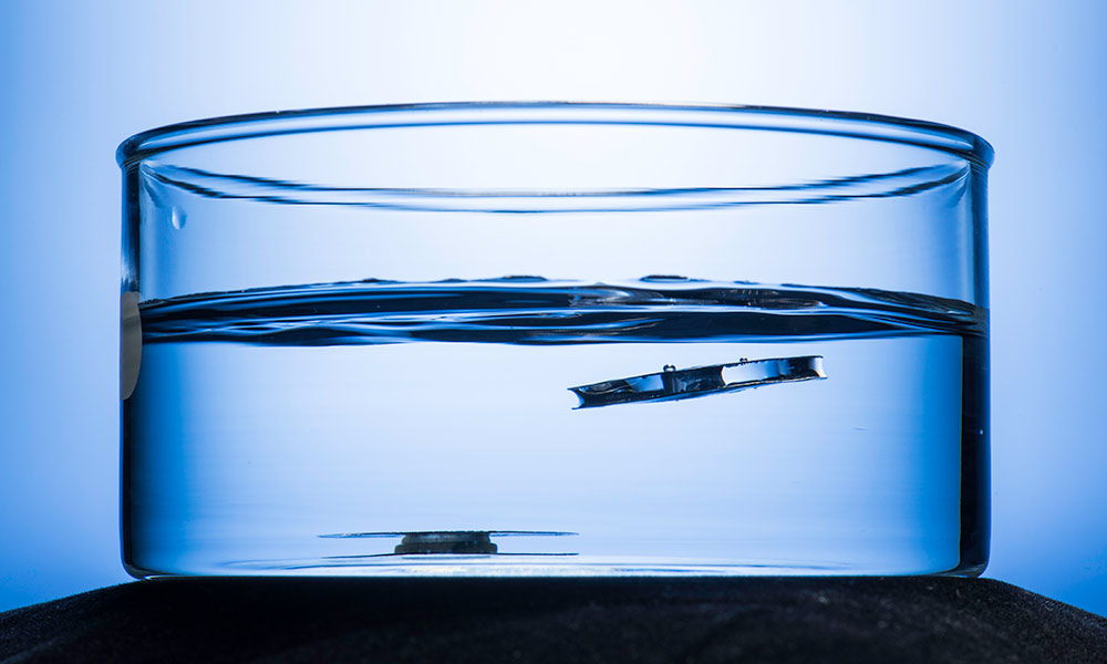 A metallic structure etched by lasers, right, floats to the top on the water's surface
