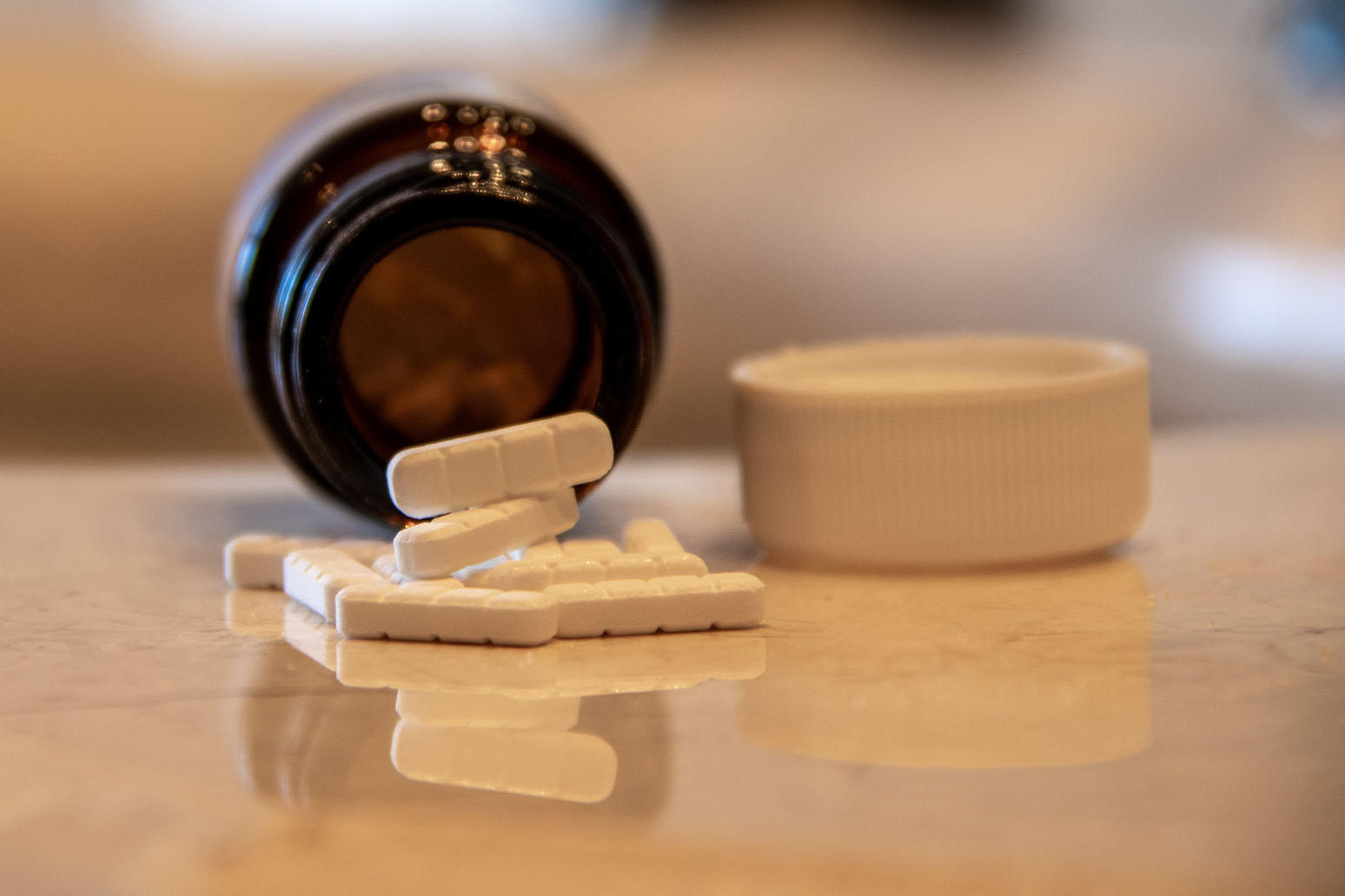 Pills spill from an open bottle.