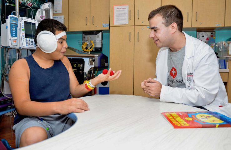 Medical student magic therapist, Harrison Pravder, engaging a pediatric patient in magic therapy at Stony Brook Children’s Hospital.