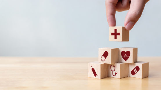 A hand places tiny building blocks in a pile.