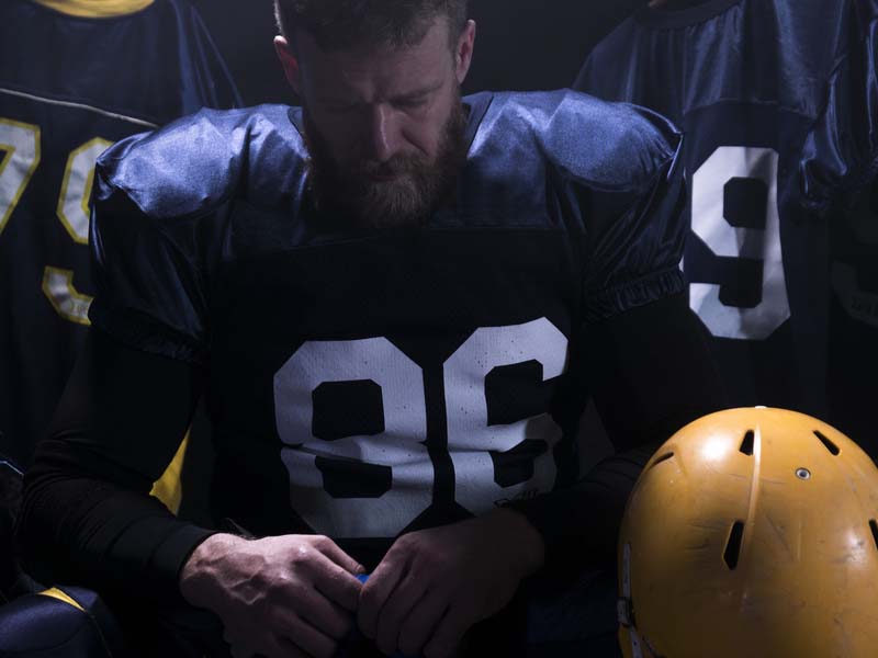 A football player sits in uniform.