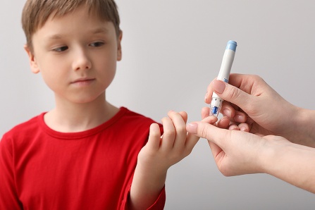 An adult tests a child's blood sugar levels.