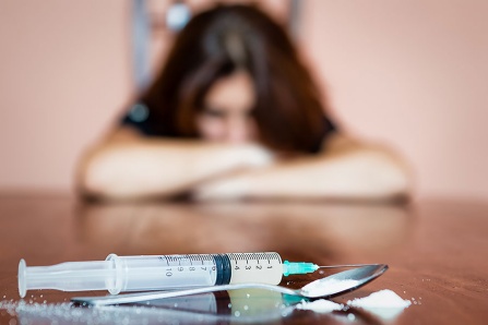 A woman stares at a syringe.
