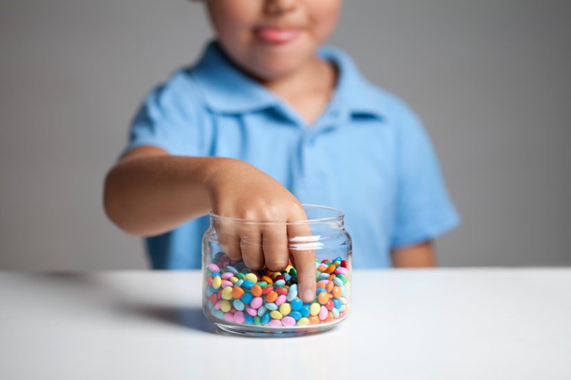 A child reaches into a candy jar.