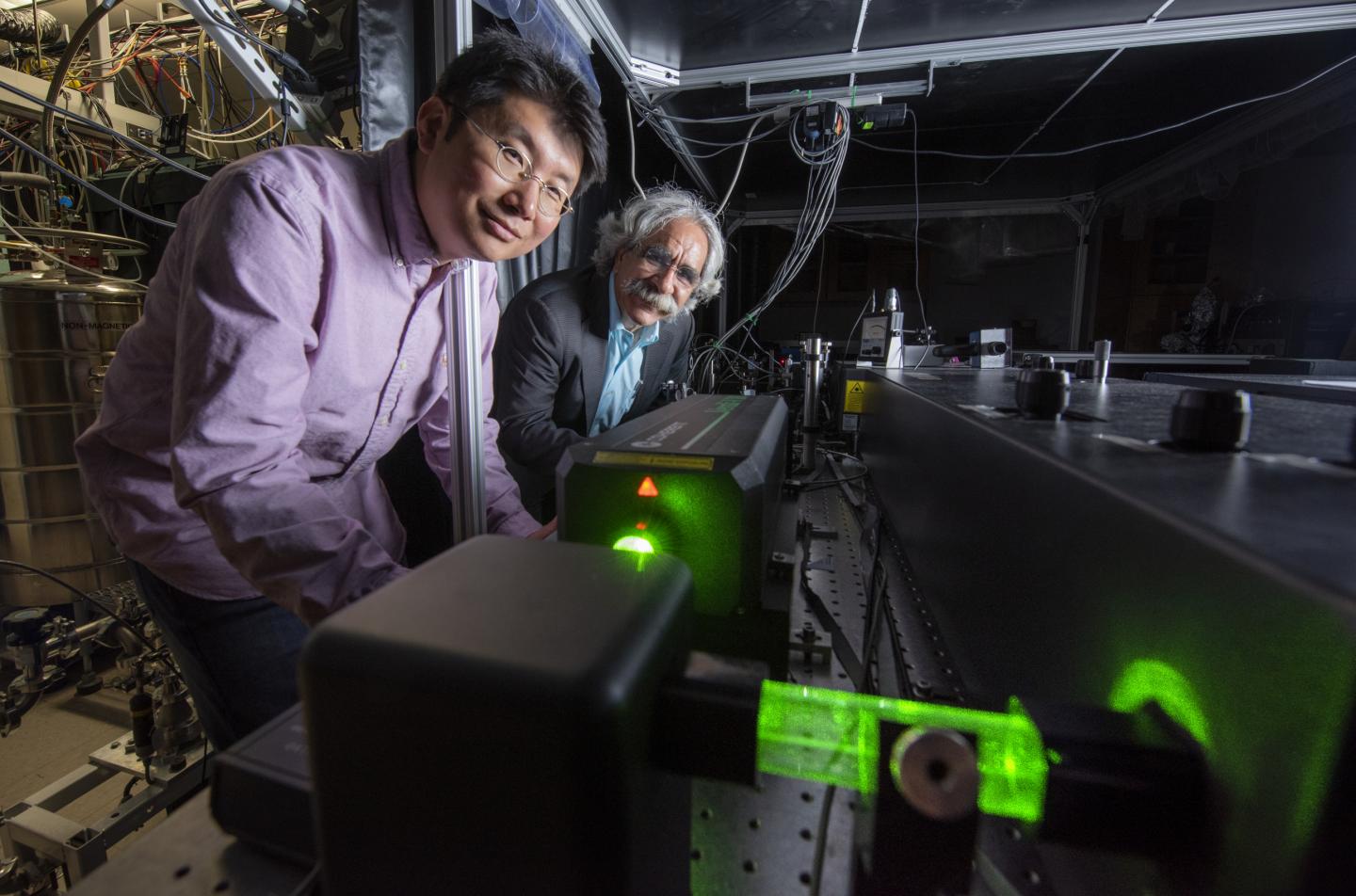Two scientists look at a vacuum microscope.