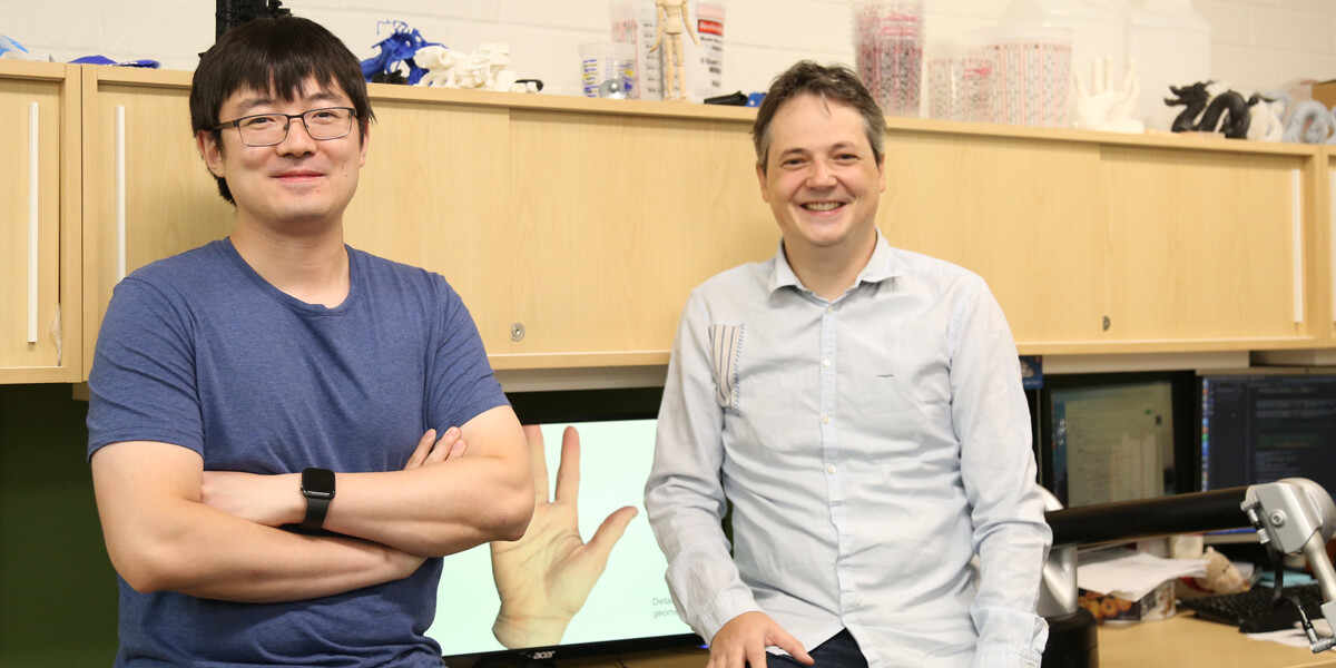 Researchers pose in front of hand model.
