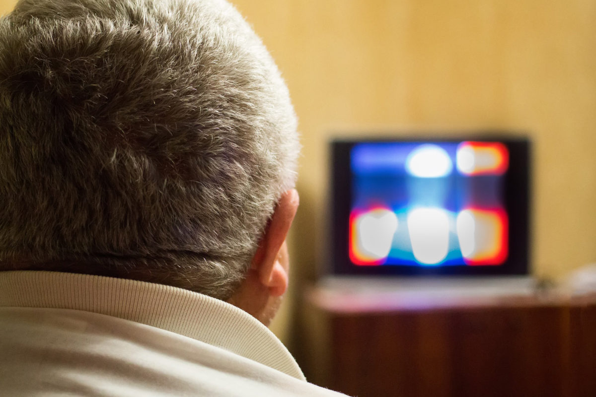 A man watches a television show.
