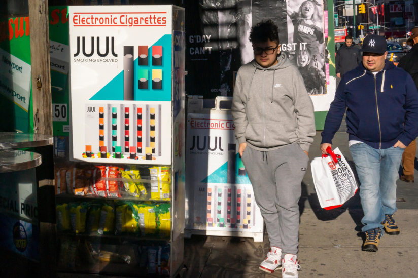 A teen walks by a vape advertisement