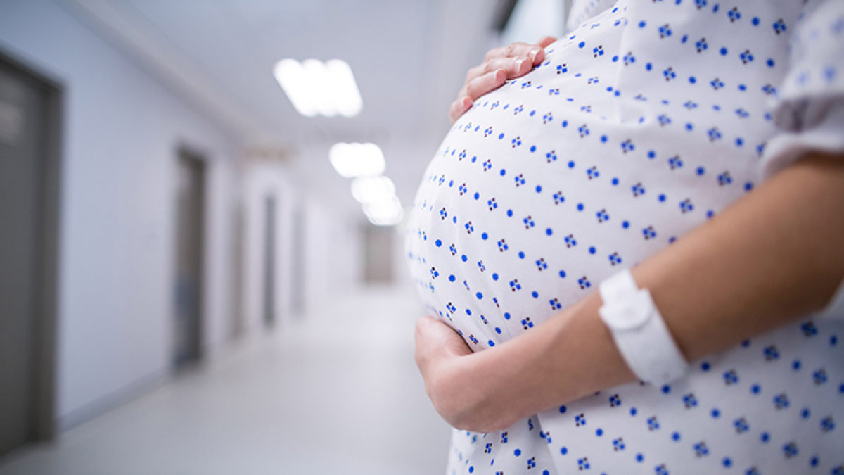 A pregnant person holds their stomach.