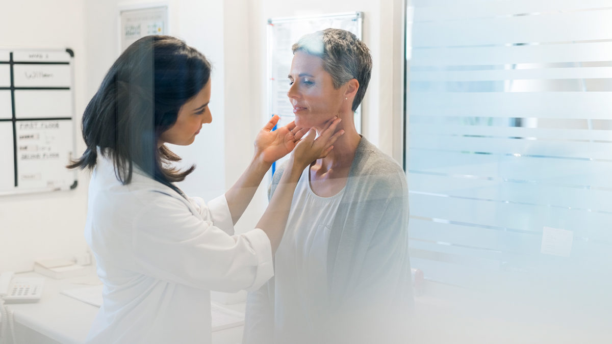 A doctor feels a woman's neck.
