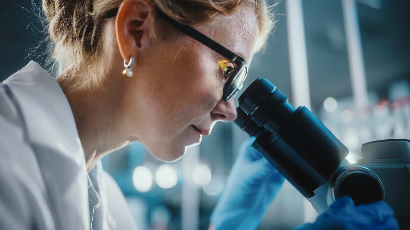 a researcher looking into a microscrope
