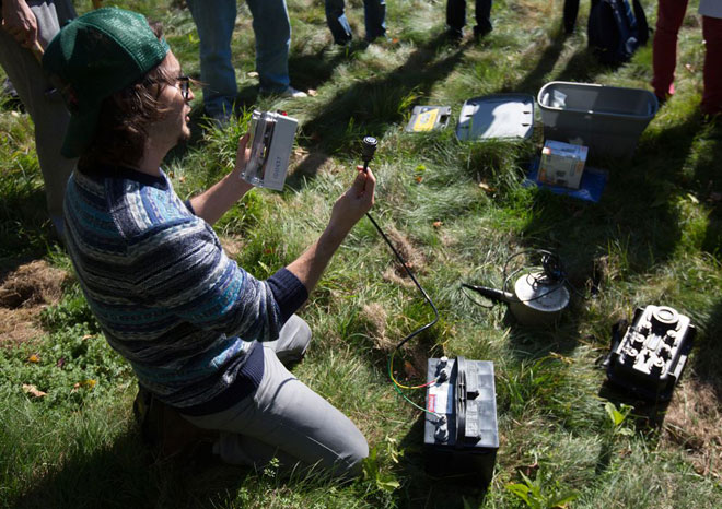 Doctoral student Diego Quiros shows undergrads how to test equipment before burying it underground.