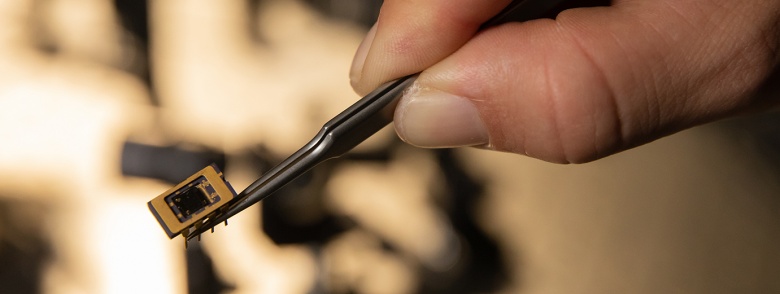 Tweezers hold a tiny chip.